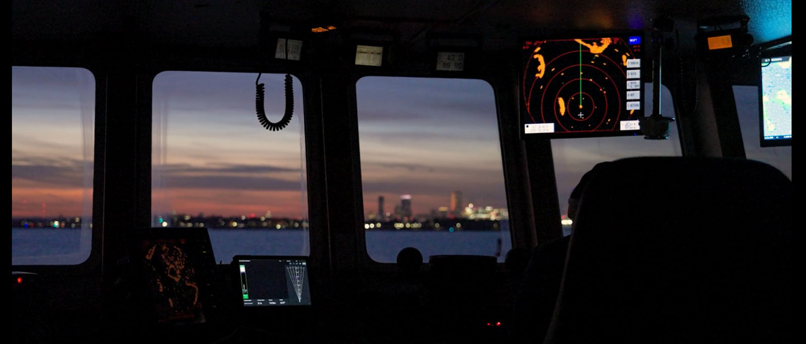 Ship bridge at sunrise with radar screens and navigation displays overlooking the water