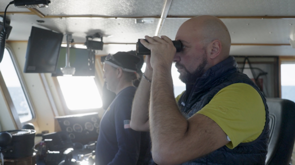 Side view of a man looking through binoculars
